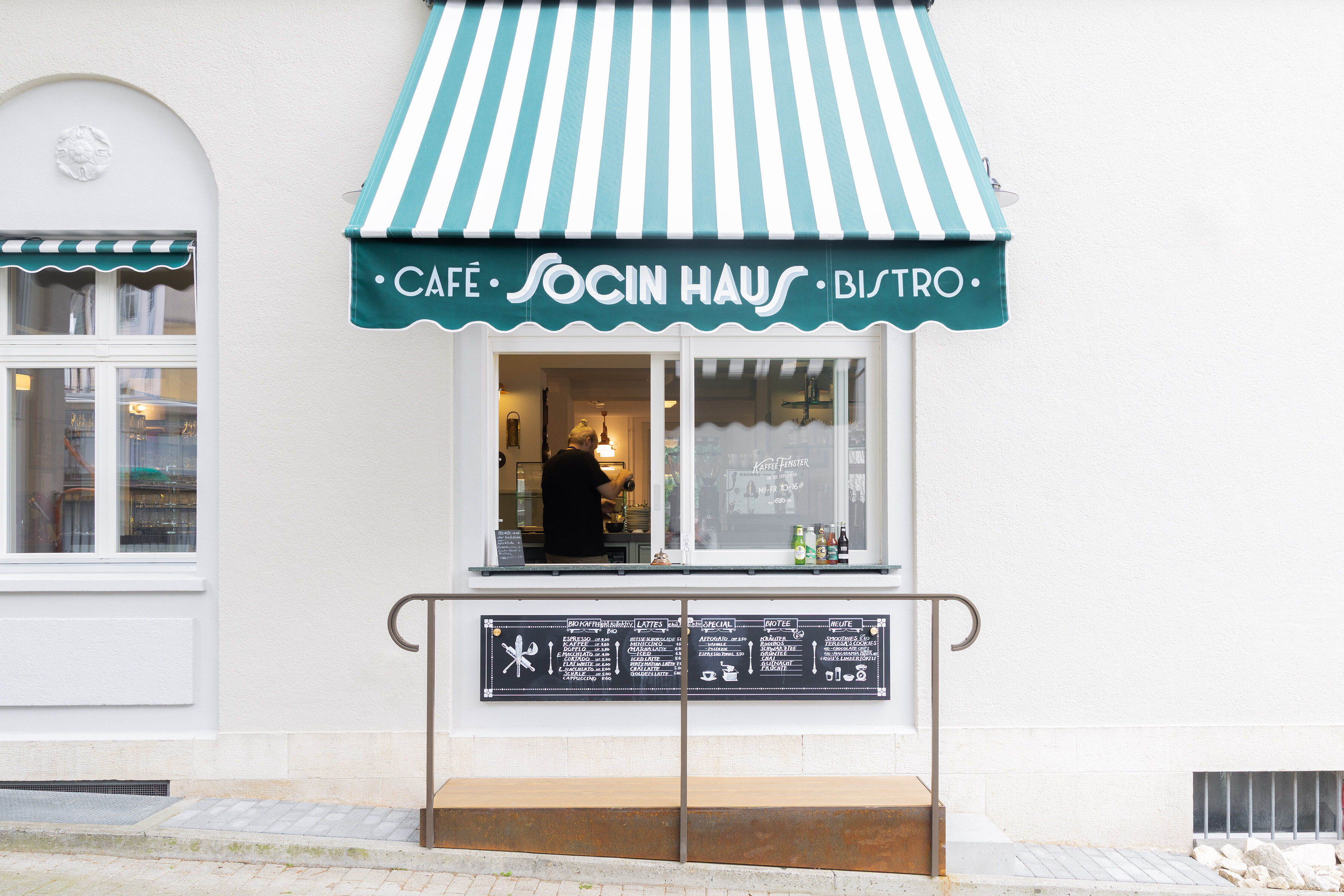Aussenansicht des Kaffeefensters, offene, gestreifte Storen