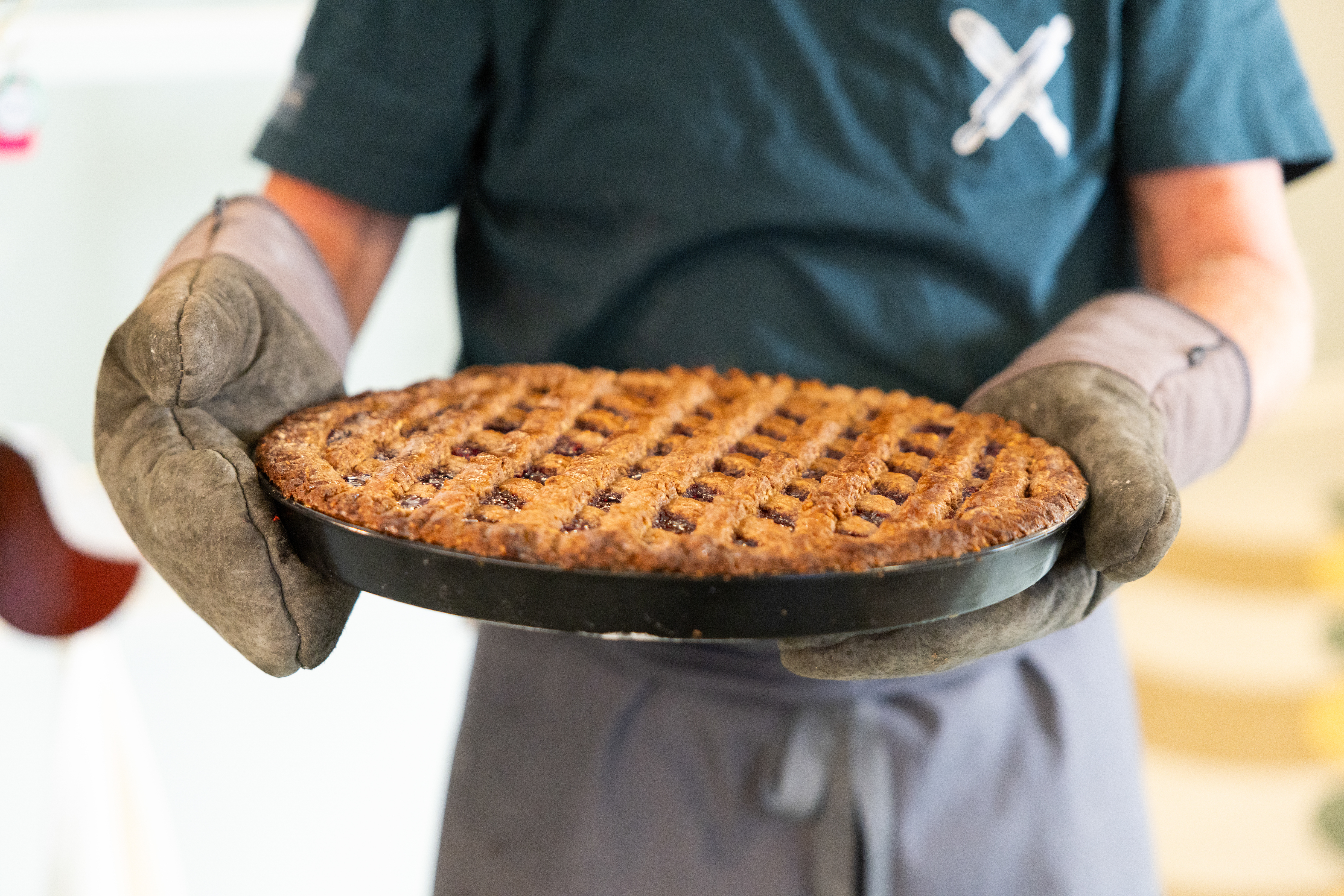 Eine Linzertorte frisch aus dem Ofen, Nahaufnahme mit Backhandschuhen