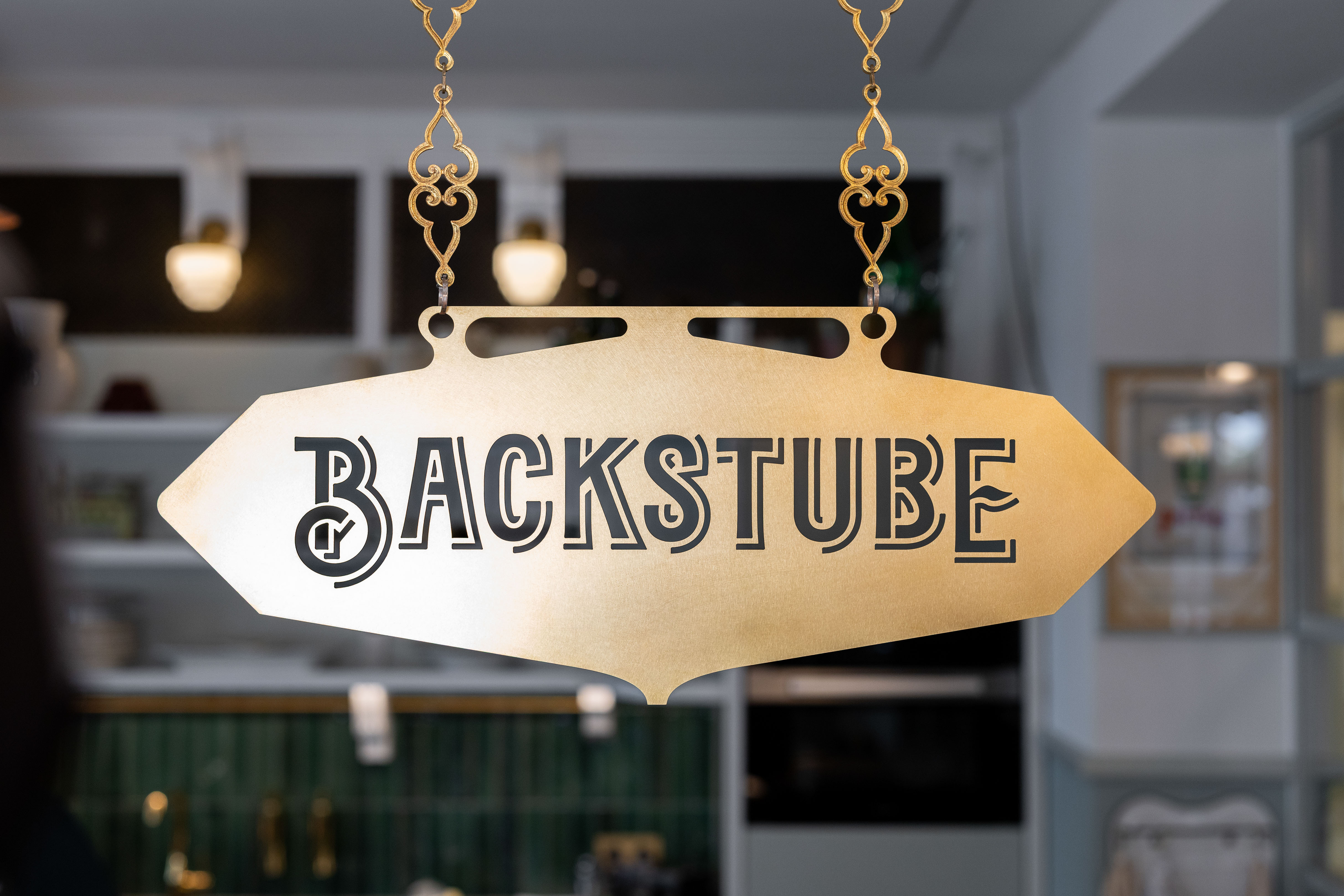 Ein Messingschild vor dunklem Hintergrund, beschriftet mit «Backstube»